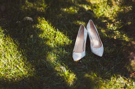 Bride wedding shoes with high heels and silver brilliant earrings on sheep's clothingの写真素材