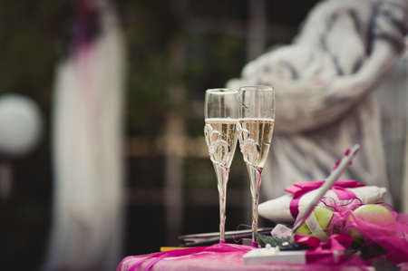 Two glasses of champagne on the background of the wedding bouquet of pink roses. Soft focus, selective focusの写真素材