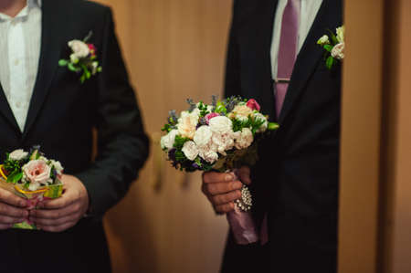 Wedding groom with bride's bouquet of flowers outsideの写真素材