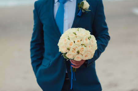 Wedding groom with bride's bouquet of flowers outsideの写真素材