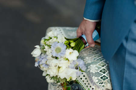 Wedding groom with bride's bouquet of flowers outsideの写真素材