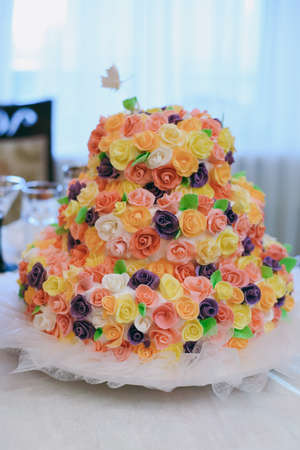 Beautiful white and colored wedding cake. A bride and a groom is cutting their wedding cakeの写真素材