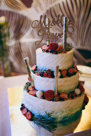 Beautiful white and colored wedding cake. A bride and a groom is cutting their wedding cakeの写真素材
