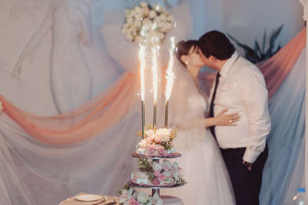 Beautiful white and colored wedding cake. A bride and a groom is cutting their wedding cakeの写真素材