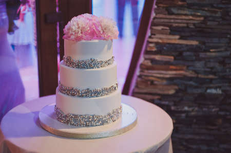 Beautiful white and colored wedding cake. A bride and a groom is cutting their wedding cakeの写真素材