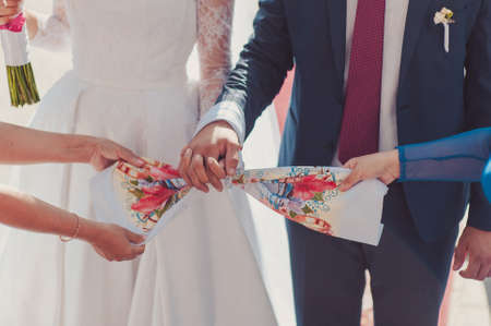 Hands of bride and groom tied Wedding towels. The priest binds the bride's hand towel. hands of young couples in the church. couple holding hands in towel at church ceremony. Wedding day.の写真素材