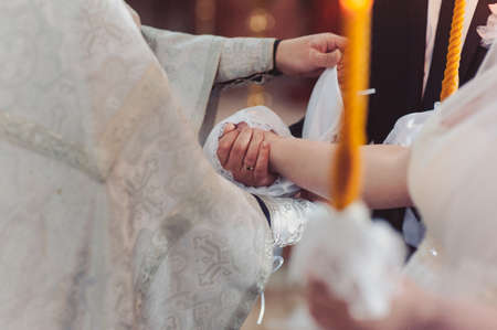 Hands of bride and groom tied Wedding towels. The priest binds the bride's hand towel. hands of young couples in the church. couple holding hands in towel at church ceremony. Wedding day.の写真素材