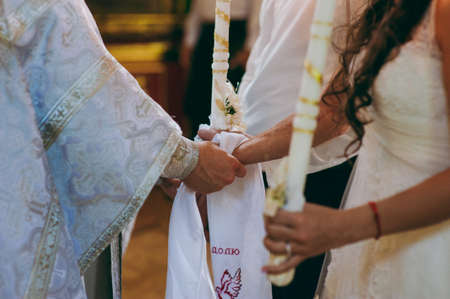 Hands of bride and groom tied Wedding towels. The priest binds the bride's hand towel. hands of young couples in the church. couple holding hands in towel at church ceremony. Wedding day.の写真素材