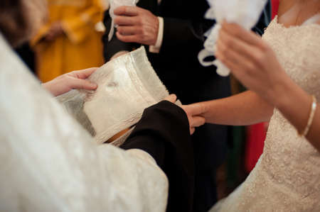 Hands of bride and groom tied Wedding towels. The priest binds the bride's hand towel. hands of...