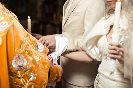 Hands of bride and groom tied Wedding towels. The priest binds the bride's hand towel. hands of...