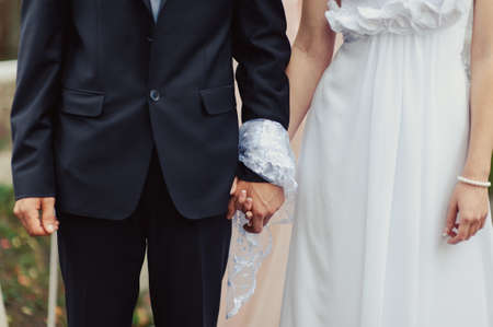 Hands of bride and groom tied Wedding towels. The priest binds the bride's hand towel. hands of young couples in the church. couple holding hands in towel at church ceremony. Wedding day.の写真素材