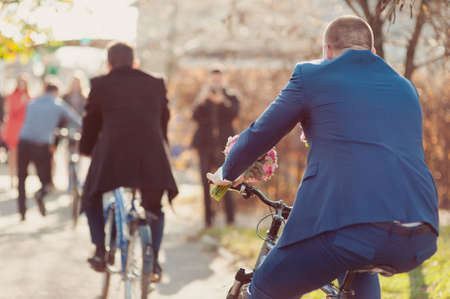 The groom in a blue suit riding a bicycle weddingの写真素材
