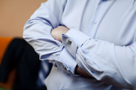 The groom fastens the cufflink on the shirt sleeve close-upの写真素材
