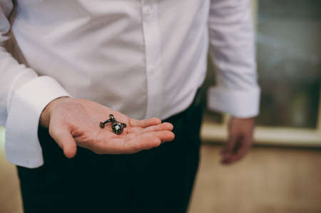 The groom fastens the cufflink on the shirt sleeve close-upの写真素材