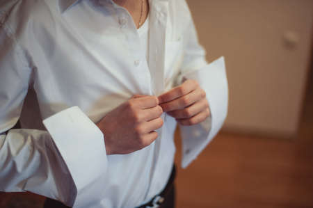 man buttoning his shirt