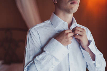 man buttoning his shirtの写真素材