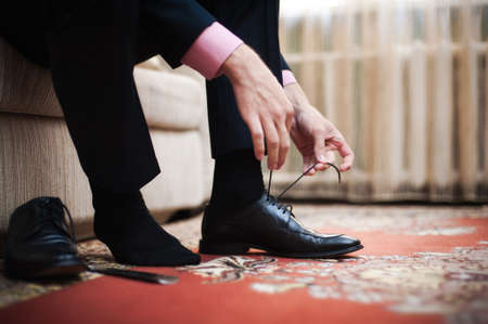 The man wears shoes. Tie the laces on the shoes. Men's style. Professions. To prepare for work, to...