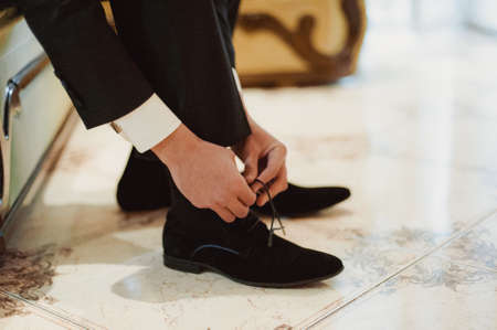 The man wears shoes. Tie the laces on the shoes. Men's style. Professions. To prepare for work, to...