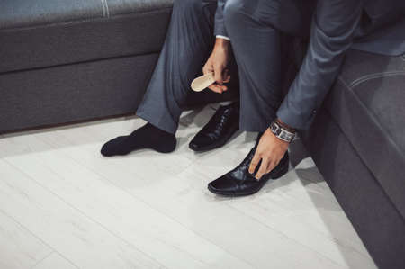 The man wears shoes. Tie the laces on the shoes. Men's style. Professions. To prepare for work, to the meeting.の写真素材
