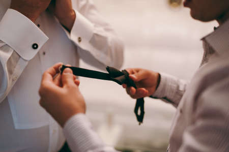 The groom puts on a butterfly. A business man dresses a butterfly.