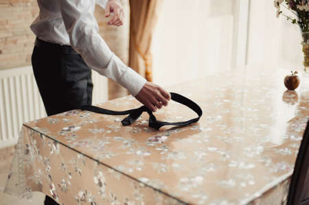 The groom puts on his tie. A business man is dressing a tie.