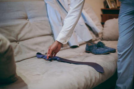 The groom puts on his tie. A business man is dressing a tie.の写真素材