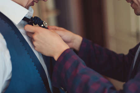 The groom puts on his tie. A business man is dressing a tie.の写真素材