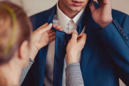 The groom puts on his tie. A business man is dressing a tie.の写真素材