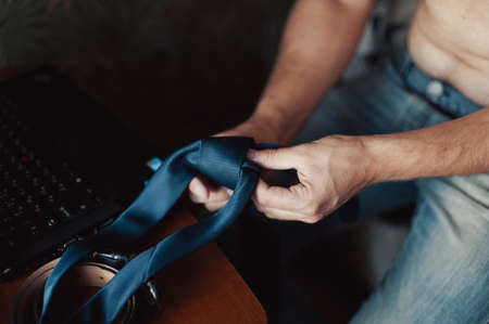 The groom puts on his tie. A business man is dressing a tie.の写真素材