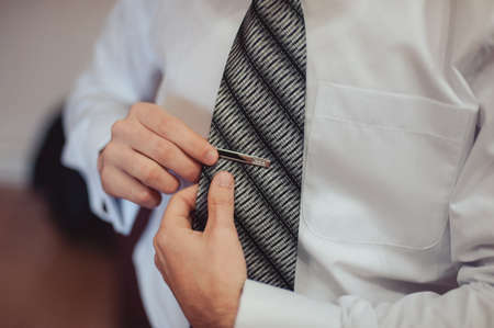 The groom puts on his tie. A business man is dressing a tie.の写真素材