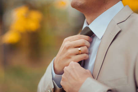 The groom puts on his tie. A business man is dressing a tie.の写真素材
