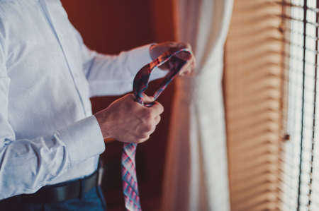 The groom puts on his tie. A business man is dressing a tie.の写真素材