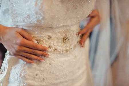 Fashionable bridesmaids dresses helped wear bow on back of wedding dress bride. Morning wedding day.の写真素材