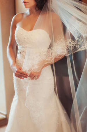 Fashionable bridesmaids dresses helped wear bow on back of wedding dress bride. Morning wedding day.の写真素材