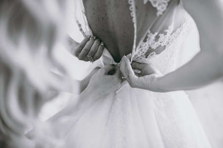 Fashionable bridesmaids dresses helped wear bow on back of wedding dress bride. Morning wedding day.の写真素材