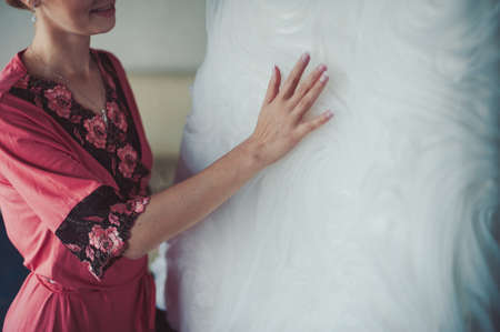 Fashionable bridesmaids dresses helped wear bow on back of wedding dress bride. Morning wedding day.の写真素材
