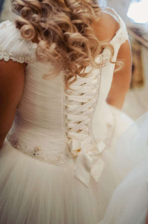 Fashionable bridesmaids dresses helped wear bow on back of wedding dress bride. Morning wedding day.の写真素材
