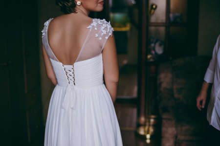 Fashionable bridesmaids dresses helped wear bow on back of wedding dress bride. Morning wedding day.の写真素材