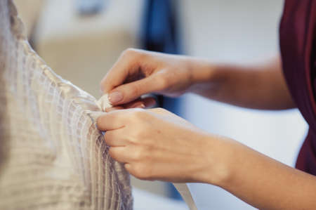 Fashionable bridesmaids dresses helped wear bow on back of wedding dress bride. Morning wedding day.の写真素材
