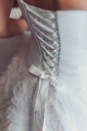 Fashionable bridesmaids dresses helped wear bow on back of wedding dress bride. Morning wedding day.の写真素材