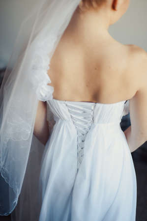 Fashionable bridesmaids dresses helped wear bow on back of wedding dress bride. Morning wedding day.の写真素材
