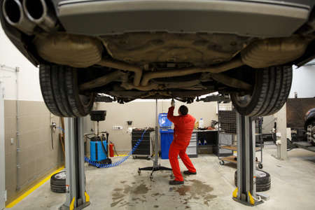 Car mechanics checking up pressure in tires at workshopの写真素材