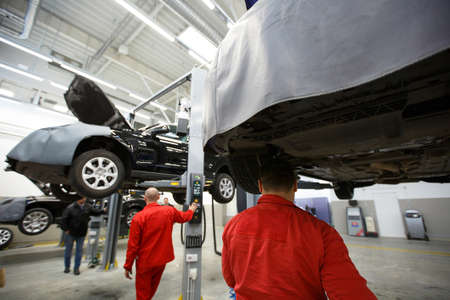 Car mechanics checking up pressure in tires at workshop