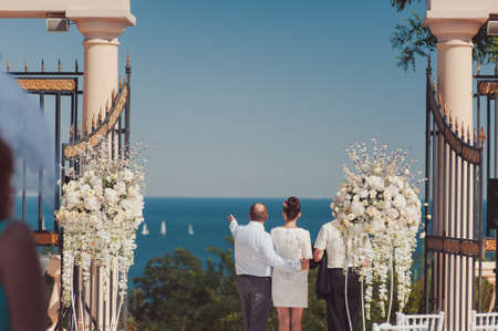 Wedding. Happy couple day after wedding. Beautiful couple embrace with open arms looking at the sea in the distance. Wedding couple staying over beautiful landscape.の写真素材