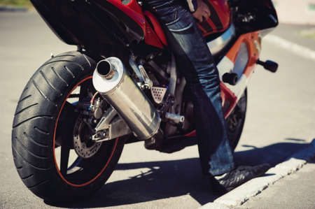 A man on a motorcycle stands on the sidelinesの写真素材