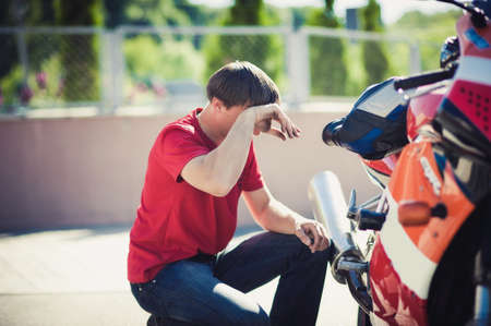 Close up Young White Guy Fixing Some Parts of his Blue Motorbike Using his Bare Hands.の写真素材