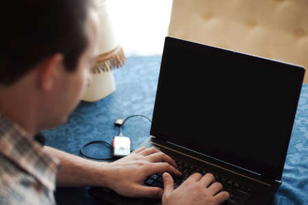 Businessperson typing on keyboard placed on office desk with various items and looking at a blank computer screen. Mock upの写真素材