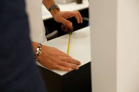 Worker measuring steel with measuring tape