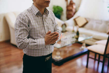 Closeup on a asian man with his hands folded in prayerの写真素材