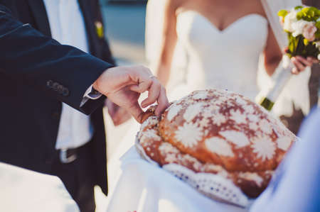 Closeup photo of bride and groom breaking traditional loafの写真素材